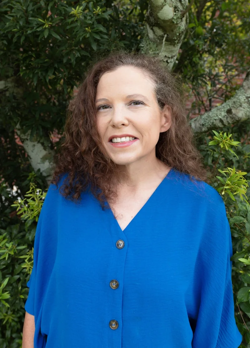 Laura Florey wearing a blue blouse outdoors beside a tree